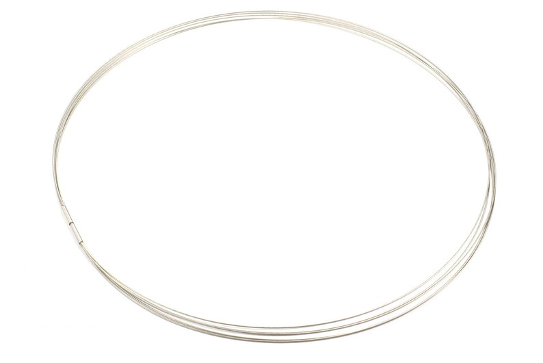 May include: A silver-colored necklace with three thin, circular strands. The necklace has a simple design and a clasp closure. The jewelry is displayed against a white background.