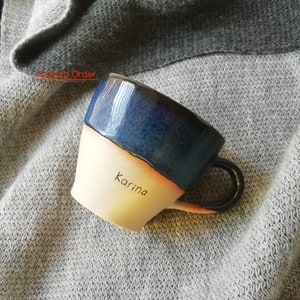 May include: A ceramic mug with a blue and white glaze. The mug has a handle and the name "Karina" is written on the side.