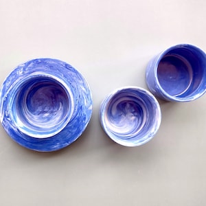 May include: Three blue and white marbled ceramic bowls of different sizes. The bowls have a swirling pattern of blue and white.