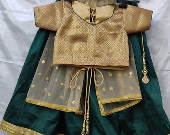 Könnte beinhalten: Ein grünes und goldenes Mädchen-Rock-Set mit einem gold bestickten Oberteil, einem grünen Rock mit goldenen Verzierungen und einem durchsichtigen goldenen Netz-Dupatta mit goldenen Punkten.