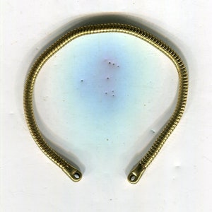 Puede incluir: Un brazalete de cadena de serpiente de color dorado con un diseño simple. El brazalete está hecho de una serie de pequeños eslabones entrelazados que crean una cadena suave y flexible.