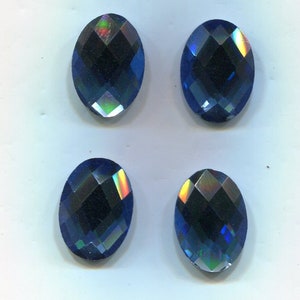 Könnte beinhalten: Vier regenbogenfarbene blaue, ovale Strasssteine. Die Strasssteine haben ein facettierendes Design und eine dunkelblaue Farbe.