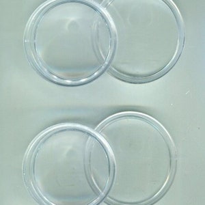 Può includere: Quattro capsule per monete in plastica trasparente, due impilate sopra altre due.