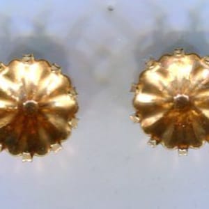 Op de afbeelding: Een paar gouden oorbellen met een gegolfd ontwerp. De oorbellen zijn rond en hebben een gladde, glanzende afwerking.