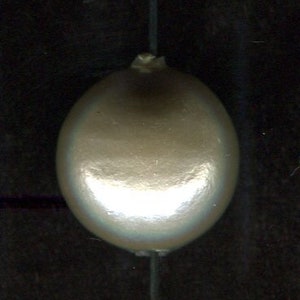 Pode incluir: Uma única conta de forma oval, de cor branca perolada, com um furo no centro para enfiar.