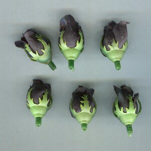 Könnte beinhalten: Sechs schwarze Stoffrosen-Knospen mit grünen Plastikstielen. Die Rosenknospen haben ein grünes und schwarzes Muster.