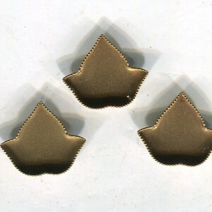 May include: Three gold-colored metal leaf-shaped embellishments with a scalloped edge.