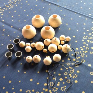 Puede incluir: Un conjunto de cuentas de madera y esferas de madera con agujeros. Hay cuatro esferas m&aacute;s grandes y una variedad de cuentas m&aacute;s peque&ntilde;as. Tambi&eacute;n hay cuatro peque&ntilde;as tazas negras y un cord&oacute;n negro.