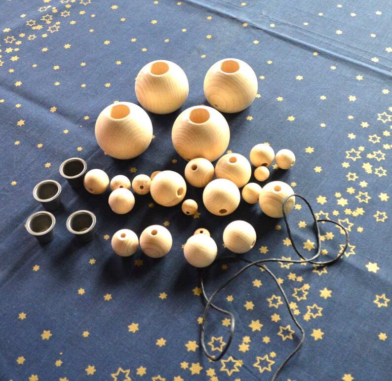 Puede incluir: Un conjunto de cuentas de madera y esferas de madera con agujeros. Hay cuatro esferas m&aacute;s grandes y una variedad de cuentas m&aacute;s peque&ntilde;as. Tambi&eacute;n hay cuatro peque&ntilde;as tazas negras y un cord&oacute;n negro.