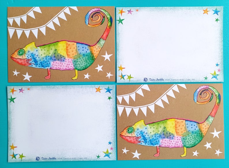 May include: Four cards with a colorful chameleon illustration. The chameleon is painted in rainbow hues and has a curled tail. White stars and a banner decorate the brown background. The cards have white blank spaces for writing.