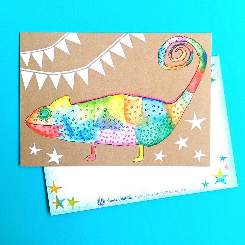 May include: A colorful watercolor illustration of a chameleon on a brown card, with white star and banner accents. The chameleon features a rainbow of colors and is the focal point of the design. A second card with star accents is visible.