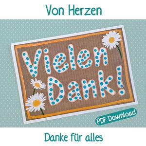May include: A rectangular card with the words "Vielen Dank!" in large, blue polka-dotted letters. The card has a brown background, an orange border, and is decorated with daisy flowers. The text "Von Herzen" and "Danke für alles" are also present.