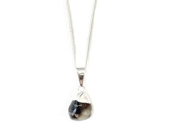 May include: A silver chain necklace with a black and white stone pendant.