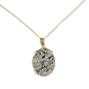 May include: A gold chain necklace with a large oval pendant made of a dark grey, sparkly stone.