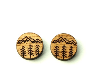 May include: A pair of wooden earrings with a laser-engraved design of mountains and trees. The earrings are round and have a natural wood finish.