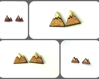 May include: A pair of wooden mountain earrings with gold accents. The earrings are shaped like triangles with a mountain peak design.
