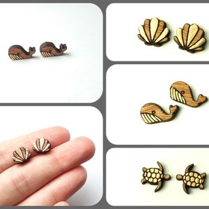 Può includere: Un set di orecchini in legno con vari disegni di vita marina. Gli orecchini sono realizzati in legno naturale e presentano una balena, una conchiglia e una tartaruga.