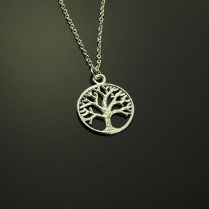 May include: A silver necklace with a tree of life pendant. The pendant is a circle with a detailed tree design.