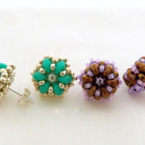 Könnte beinhalten: Vier Paar Perlenohrstecker. Zwei Paare sind türkis und silberfarben, zwei braun und lavendelfarben. Die Ohrringe sind rund mit einem floralen Design und haben silberne Stifte.