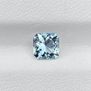 May include: A light blue square-shaped aquamarine gemstone with a faceted cut.