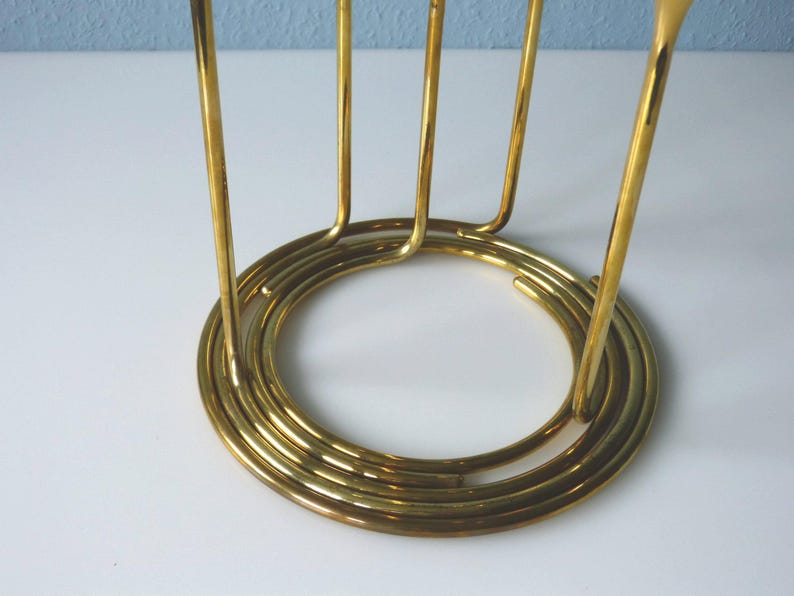 Puede incluir: Un soporte de metal dorado con una base circular y m&uacute;ltiples soportes verticales. El soporte est&aacute; dise&ntilde;ado para sostener varios art&iacute;culos, como vasos o botellas.