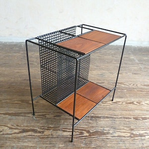 May include: A black metal wire shelf with two wooden shelves. The shelves are rectangular and have a light brown finish.