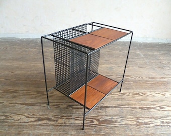 May include: A black metal wire shelf with two wooden shelves. The shelves are rectangular and have a light brown finish.