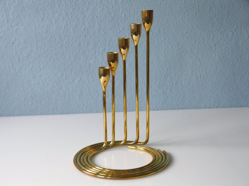 Puede incluir: Un candelero de metal dorado con cinco brazos que se enrollan en una base circular.