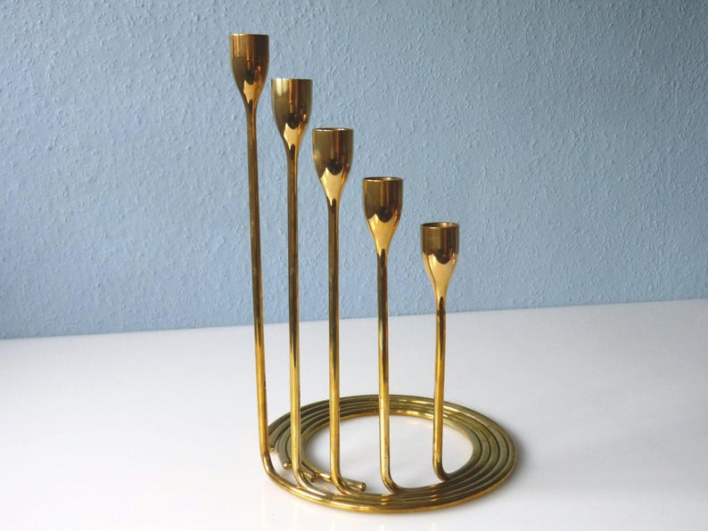 Puede incluir: Un candelero de metal dorado con cinco brazos dispuestos en espiral. El candelero est&aacute; hecho de una sola pieza de metal y tiene un acabado pulido.