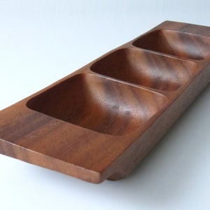 Op de afbeelding: Een houten serveerschaal met drie aparte compartimenten. De schaal is gemaakt van donkerbruin hout met een natuurlijke houtnerf.
