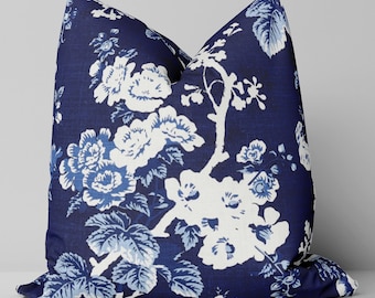 May include: A navy blue throw pillow with a white floral pattern. The pillow features a repeating design of white flowers and branches on a dark blue background.