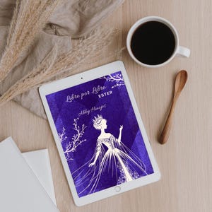 May include: A digital tablet displays a book cover with a silhouette of a woman in a gown and crown against a purple background. The text "Libro por Libro: ESTER" and "Abby Hinojos" are also visible. A cup of coffee and a wooden spoon are next to the tablet.