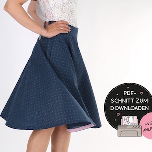 May include: A navy blue, polka-dotted skirt with a flared design. The skirt has a pink lining and a high waist. The image also includes a graphic with the text "PDF-SCHNITT ZUM DOWNLOADEN" and "+ VIDEO ANLEITUNG".