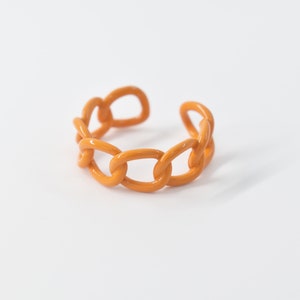 May include: A chunky orange chain ring made of plastic.