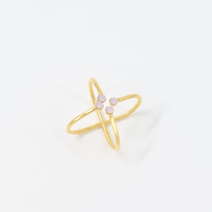 May include: A gold ring with a criss-cross design and four small, pale pink stones.