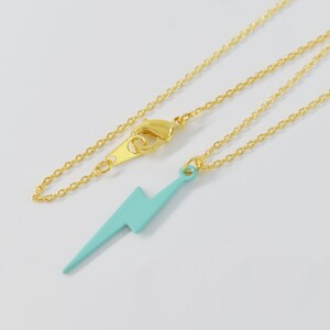 May include: A gold chain necklace with a light blue lightning bolt pendant.