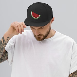 Puede incluir: Una gorra de béisbol negra con una rebanada de sandía roja y verde bordada en la parte delantera.