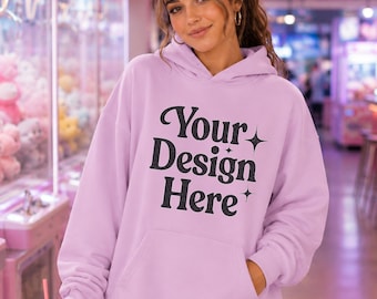 Puede incluir: Una sudadera con capucha de color morado claro que presenta un bolsillo tipo canguro frontal y el texto negro "Your Design Here" con pequeños detalles de estrellas impresos en el pecho. La prenda se combina con una minifalda blanca plisada.