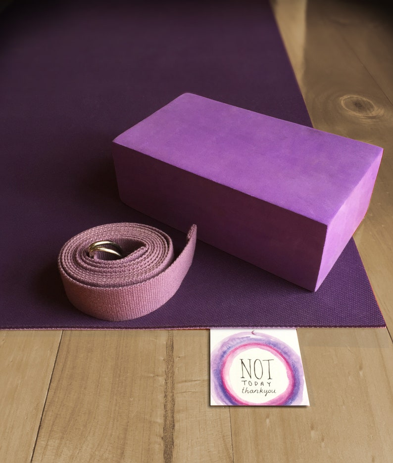 May include: Purple yoga mat with a purple yoga block and a purple yoga strap. A card with the text "NOT TODAY thank you" is on the wooden surface.