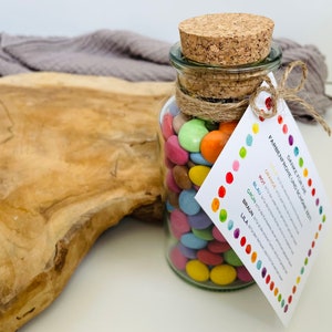 May include: A glass jar filled with colorful candy, tied with twine and a tag that reads "Danke f&uuml;r die farbenfrohe Zeit und sch&ouml;ne Zeit!" with a color key for orange, red, blue, green, brown, and purple.
