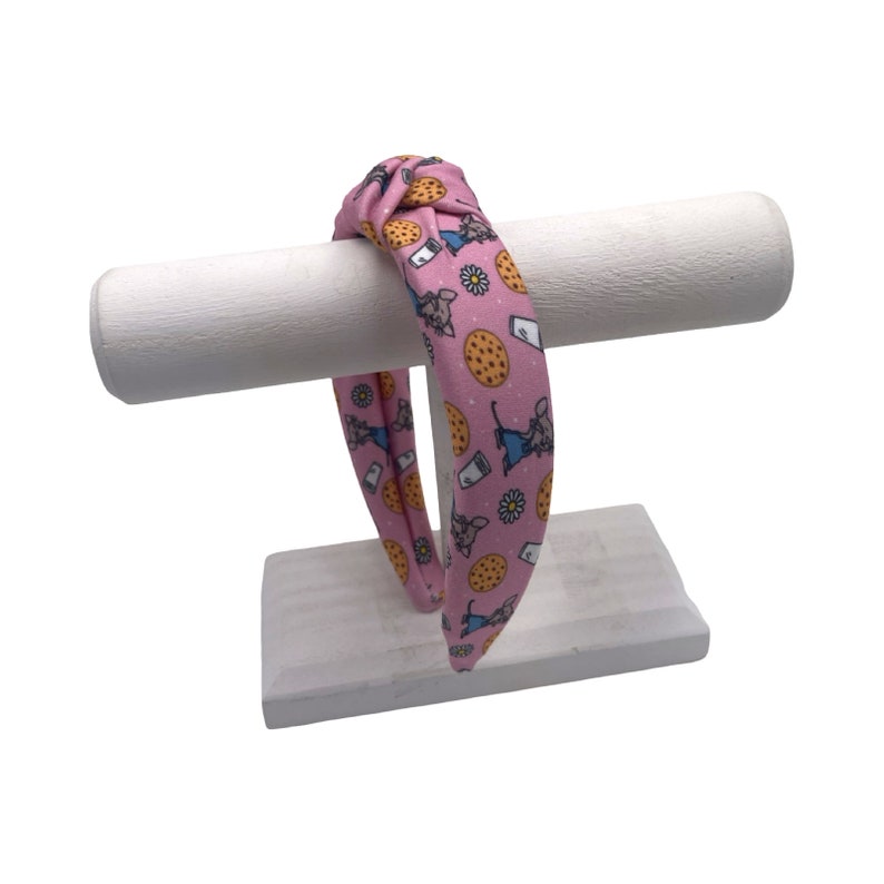 May include: Pink knotted headband with a repeating pattern of mice and cookies.