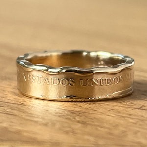 Pode incluir: Um anel de banda de ouro com uma borda texturizada e a inscrição "ESTADOS UNIDOS MEX" no lado.