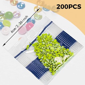 May include: A clear plastic bag filled with 200 green round rhinestones. The bag is labeled "200PCS".