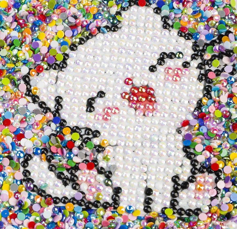 May include: A close-up of a white unicorn mosaic with iridescent and colorful beads surrounding it.