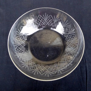 Peut inclure: Un bol en verre transparent avec un motif gravé décoratif autour du bord. Le motif présente un motif répétitif de petits carrés et triangles.