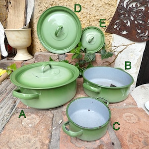 Könnte beinhalten: Eine Sammlung von Vintage-Töpfen und Deckeln aus grünem Emaille. Das Set umfasst einen großen Topf mit Deckel, zwei kleinere Töpfe und zwei Deckel. Die Töpfe haben abgerundete Griffe und eine hellgrüne Außenseite.