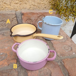 Può includere: Tre pentole e tazze vintage in smalto di vari colori. Il set comprende una casseruola gialla con bordo e manico neri, una pentola rosa con due manici e una tazza blu con manico. Lo smalto ha un aspetto invecchiato.