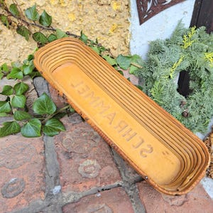 Może przedstawiać: Długi, prostokątny kosz wykonany z naturalnych materiałów. Kosz jest jasnobrązowy i ma etykietę z napisem "Schuh-Wanne".