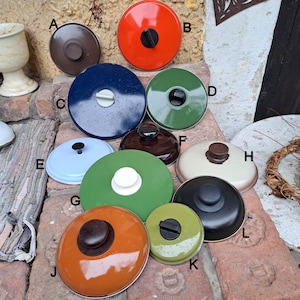 Op de afbeelding: Assortiment van 12 ronde potdeksels in verschillende kleuren, waaronder blauw, groen, rood, wit en bruin. Elk deksel heeft een knop bovenop.