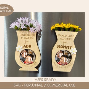 Puede incluir: Dos marcos de fotos de madera en forma de jarrón con una foto de dos niños en cada uno. Los marcos están decorados con flores y el texto "Flores recogidas a mano para" y ya sea "Abu" o "Mommy".